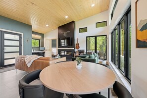 A modern living room with a round wooden table, leather sofas, and a television. - The Laurel & Sky ~ Smoky Mountains (Bryson City)