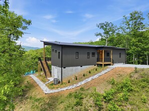 A modern two-story house with a flat roof, a covered porch, and a stone pathway leading to the entrance. - The Laurel & Sky ~ Smoky Mountains (Bryson City)
