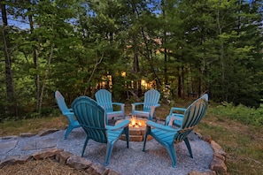 A fire pit with four Adirondack chairs arranged around it, set on a gravel surface with trees in the background. - The Laurel & Sky ~ Smoky Mountains (Bryson City)