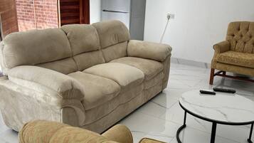 A living room with a sofa, armchair, and a small round table.