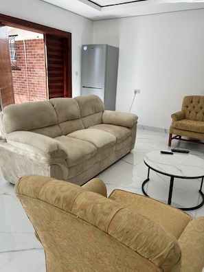 A living room with a sofa, armchair, and a small round table. -  Umhlanga   2 bedroom, 2 bathroom (Bulawayo)