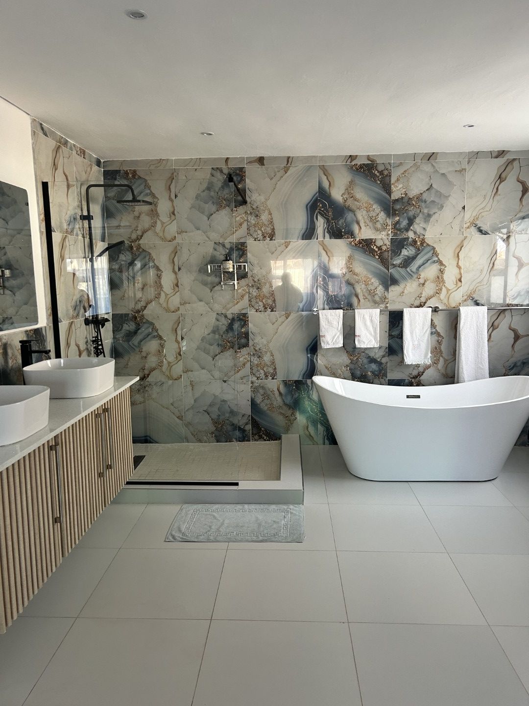 Une salle de bain moderne avec une baignoire sur pieds, deux vasques et un espace douche.