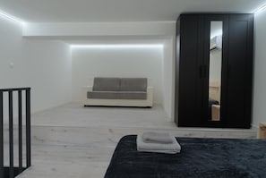 Ein Schlafzimmer mit einem Bett, einem Schlafsofa, einem Kleiderschrank und einem Spiegel.