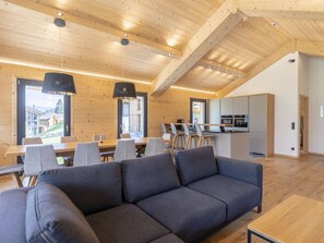 Ein modernes Interieur mit Holzboden, einer Couch, einem Esstisch mit Stühlen und einer Küchenzeile.