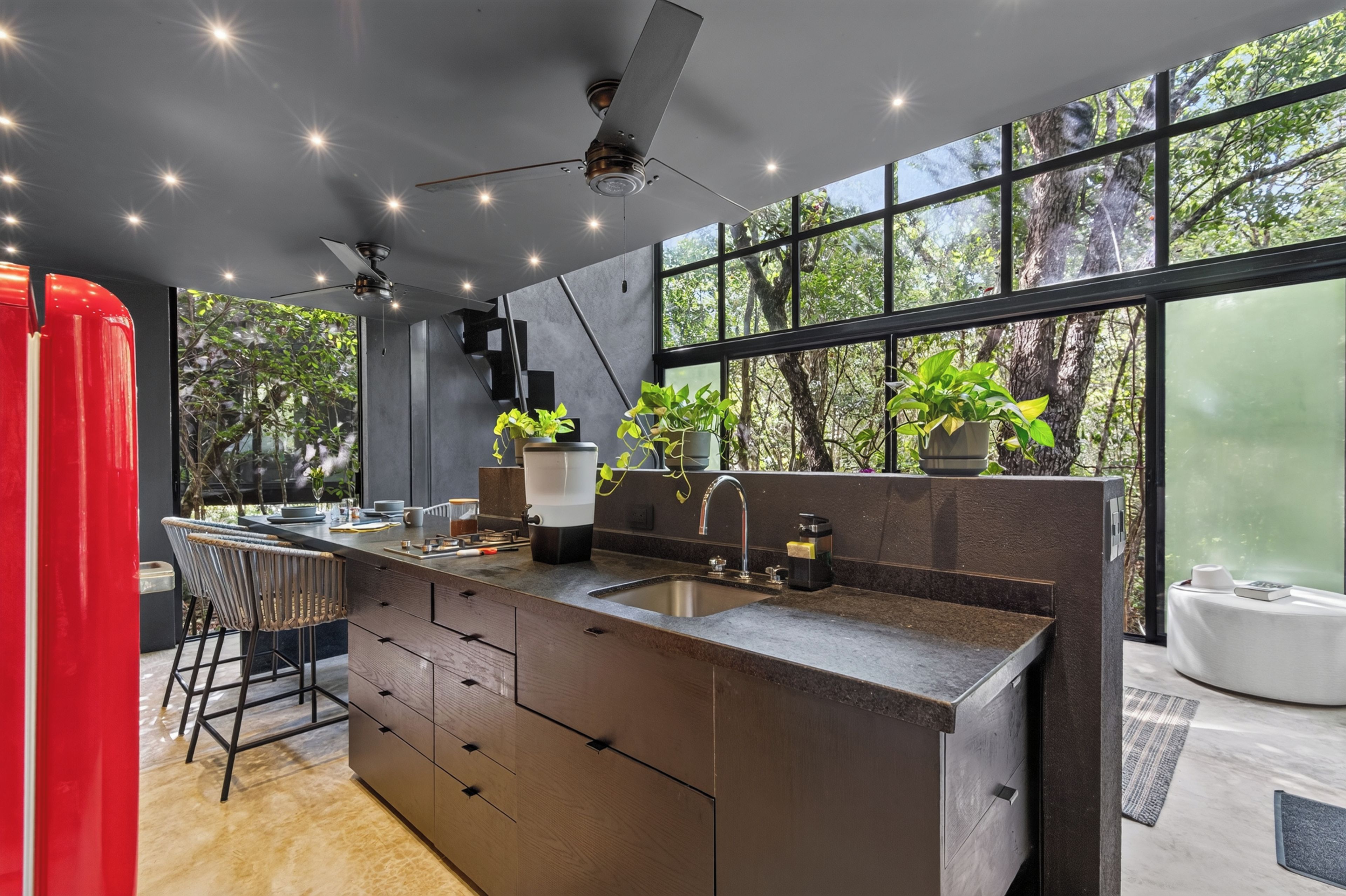 Una cucina moderna con una grande isola, sgabelli da bar, lavello integrato e una ventola a soffitto.