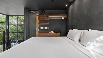 A modern bedroom with a large bed, built-in wooden shelves, and a view of greenery outside.