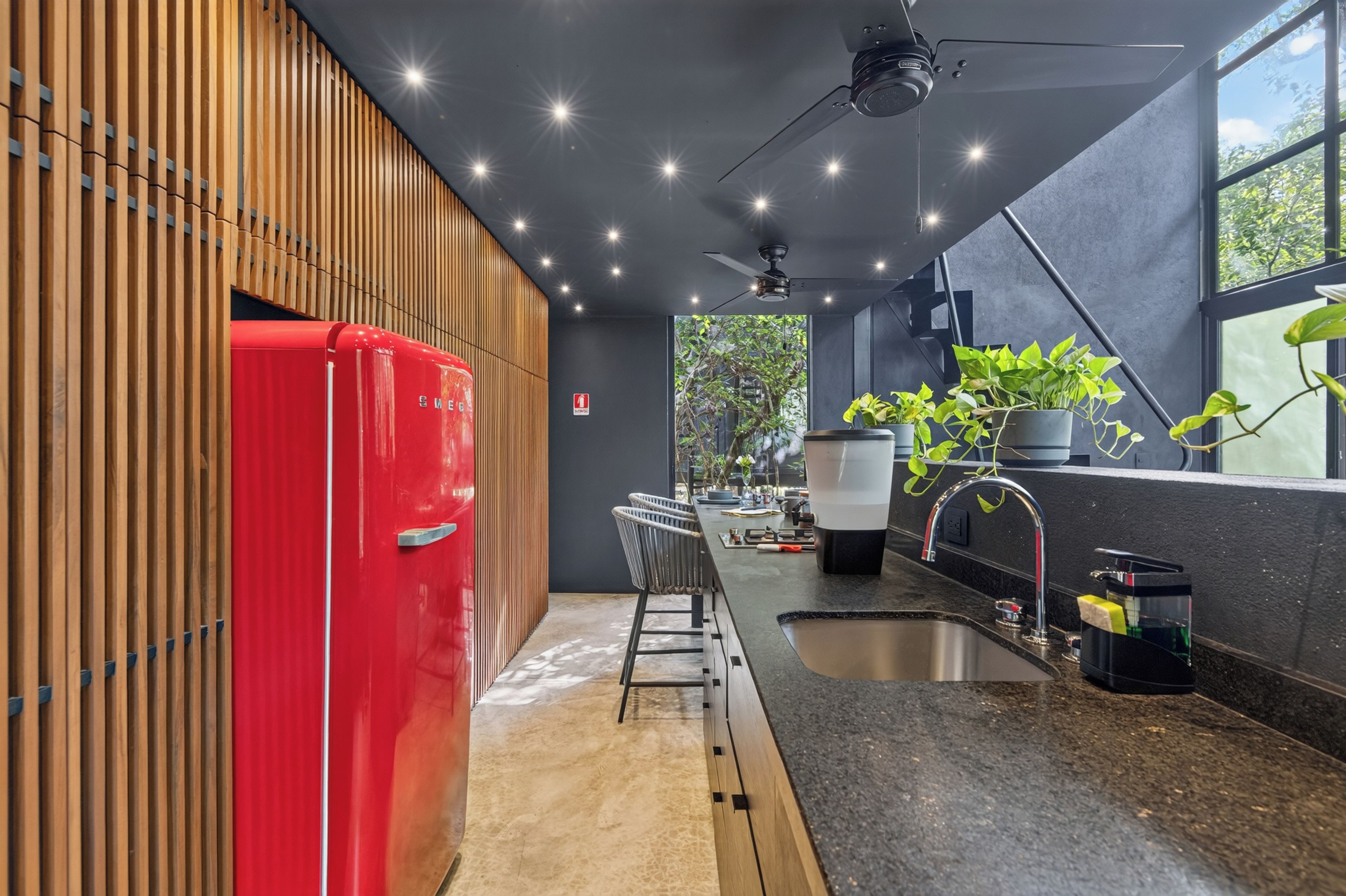 Una cocina moderna con un refrigerador rojo, un lavamanos y un ventilador de techo.