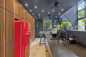 Una cocina moderna con un refrigerador rojo, un lavamanos y un ventilador de techo.