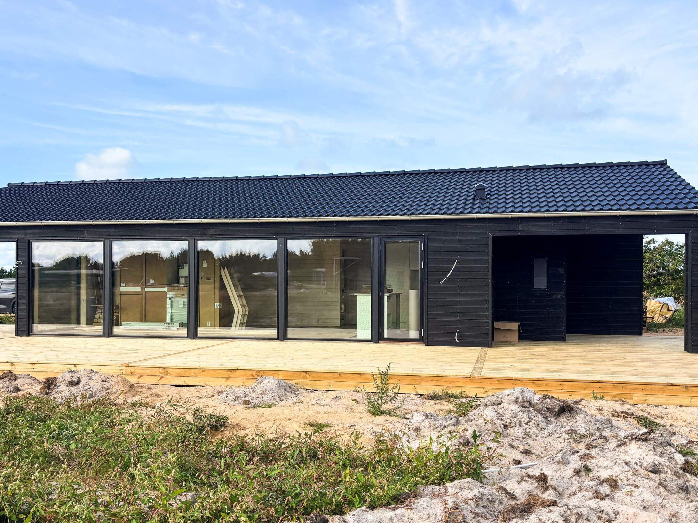 A modern building with large glass windows, a flat roof, and a wooden deck.
