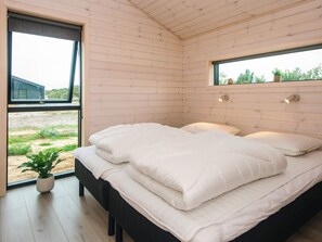 A modern bedroom with a large bed, a window, and a potted plant. - 5 Star Holiday Home in Romo (Rømø)