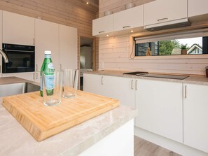 A modern kitchen with white cabinets, a wooden countertop, and a window overlooking a residential area. - 5 Star Holiday Home in Romo (Rømø)