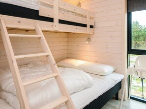 A bunk bed with a wooden ladder, a bedside table, and a window with a view of greenery. - 5 Star Holiday Home in Romo (Rømø)