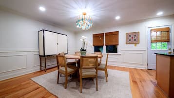 Une salle à manger avec une table ronde, des chaises, un lustre et un buffet.