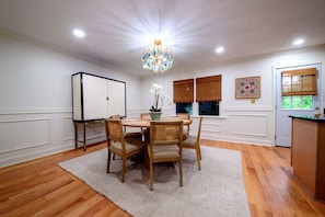 A dining room with a round table, chairs, a chandelier, and a cabinet.