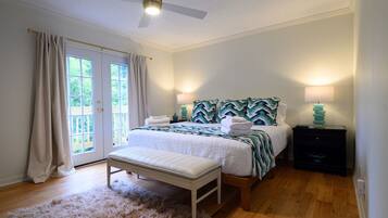 A bedroom with a bed, bench, bedside lamps, and a ceiling fan.