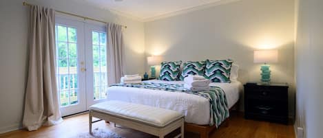 A bedroom with a bed, bench, bedside lamps, and a ceiling fan.