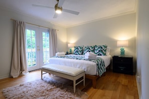 A bedroom with a bed, bench, bedside lamps, and a ceiling fan.