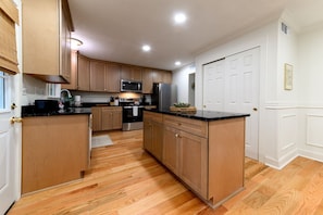 A kitchen with wooden cabinets, a microwave, a refrigerator, and a sink.