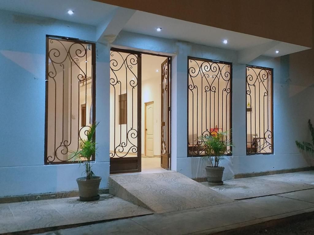 Une entrée d’immeuble agrémentée de grilles en métal décoratives, de plantes en pot et d’une rampe menant à la porte.