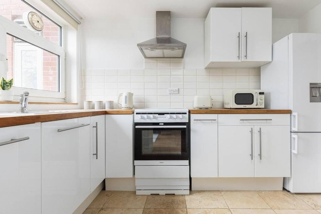 A kitchen with white cabinets, a stove, a microwave, and a refrigerator.