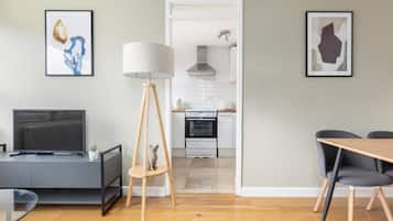 A modern living room with a TV, a lamp, a small table, and a chair.