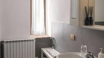 A bathroom with a white sink, a mirror, a window with a curtain, and a radiator.