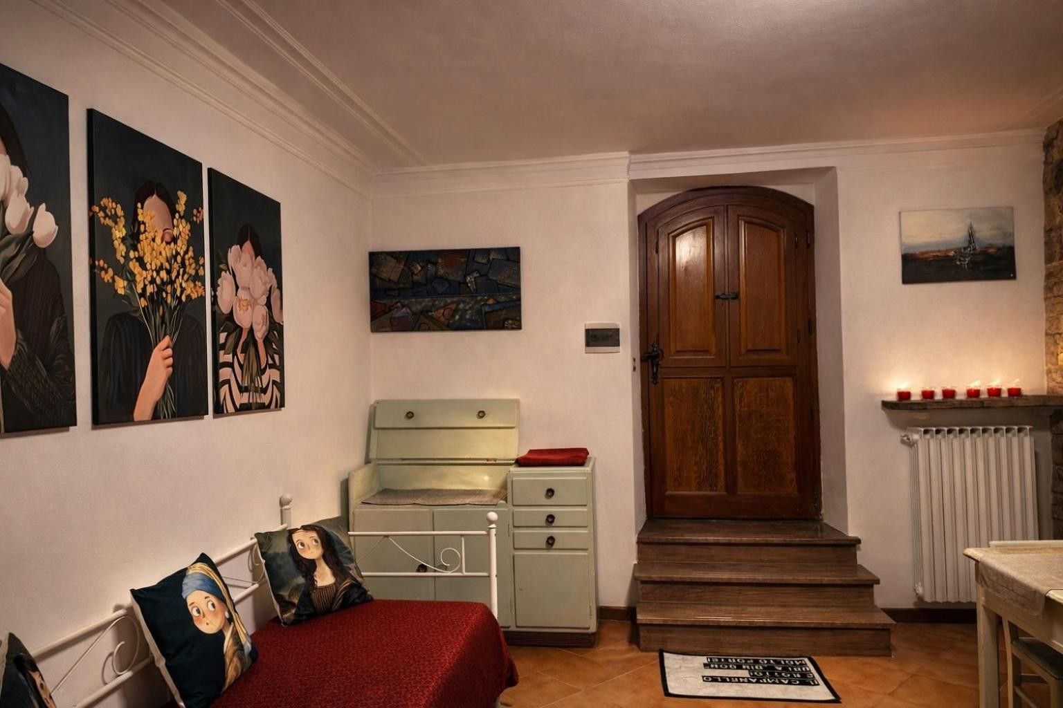 Ein Zimmer mit einem Bett, einer Kommode, einer Tür und Bildern an den Wänden.