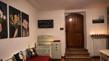Ein Zimmer mit einem Bett, einer Kommode, einer Tür und Bildern an den Wänden.