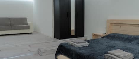 Une chambre à coucher avec un lit, une armoire, une table de chevet et un canapé.