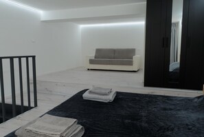 A modern living room with a sofa, a black rug, and a staircase. - Apartment Mazzini • Eleganza nel centro città (Verona)