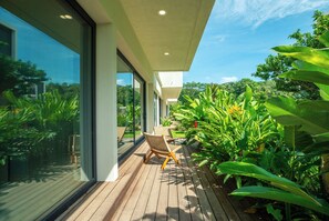 A modern house with a wooden deck, large windows, and tropical plants.