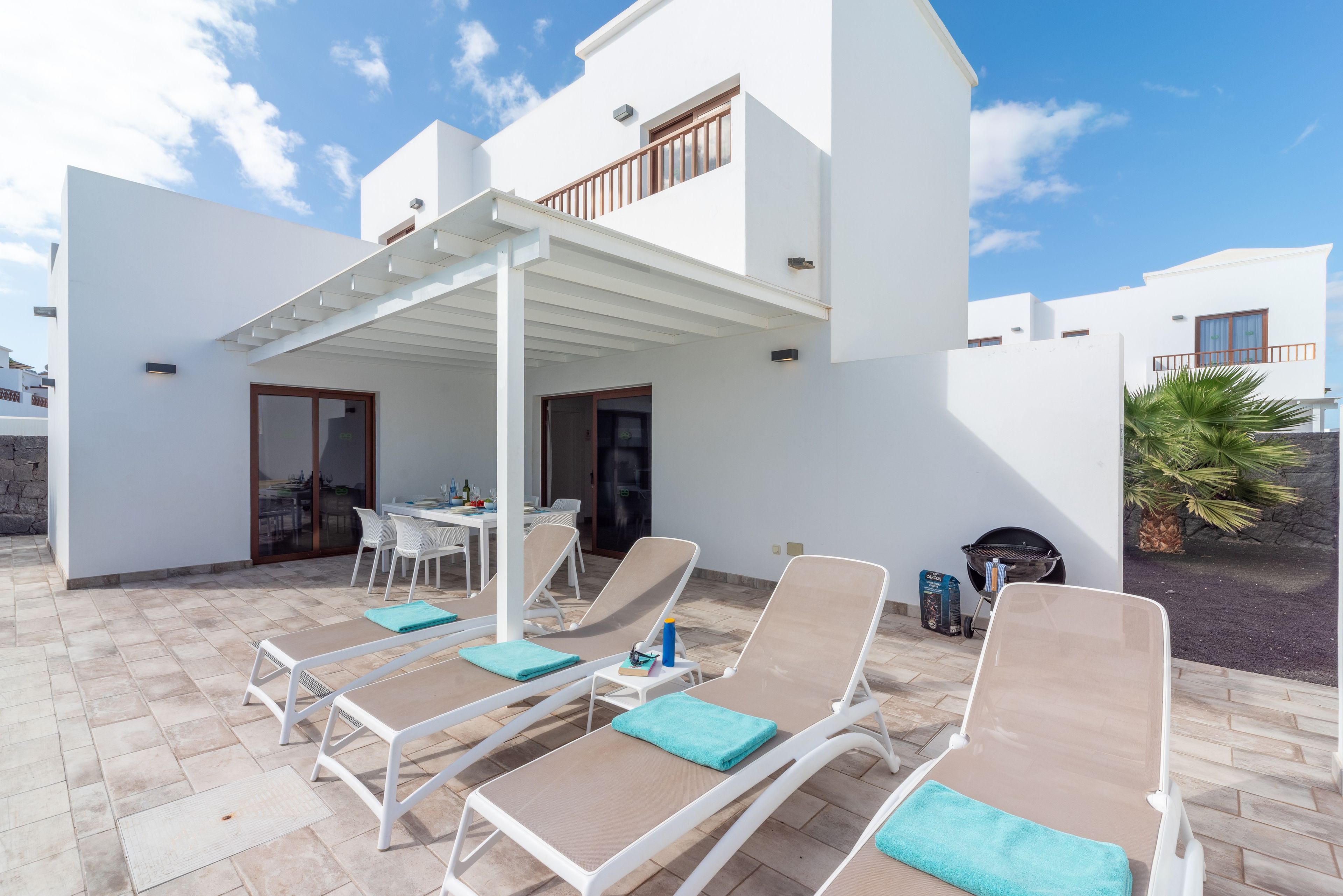 Eine moderne Außenpatio mit Lounge-Stühlen, einem Esstisch und einem Grill.