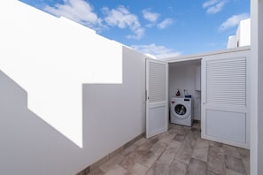 A laundry room with a washing machine and an iron. - Ereza Villas La Granja – 3-Bedroom Villas with Private Pool in Playa Blanca (Yaiza)
