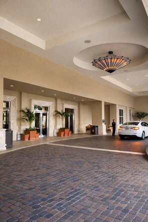 A hotel lobby with a tiled floor, a large chandelier, and a white car parked inside. - Largest 2 bd ocean view @ the palm beach Marriott (Riviera Beach)