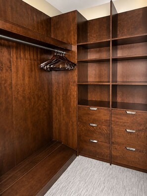A walk-in closet with wooden shelving and drawers.