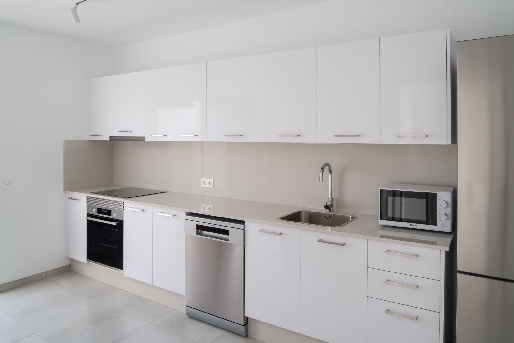A modern kitchen with white cabinetry, stainless steel appliances, and a dishwasher.
