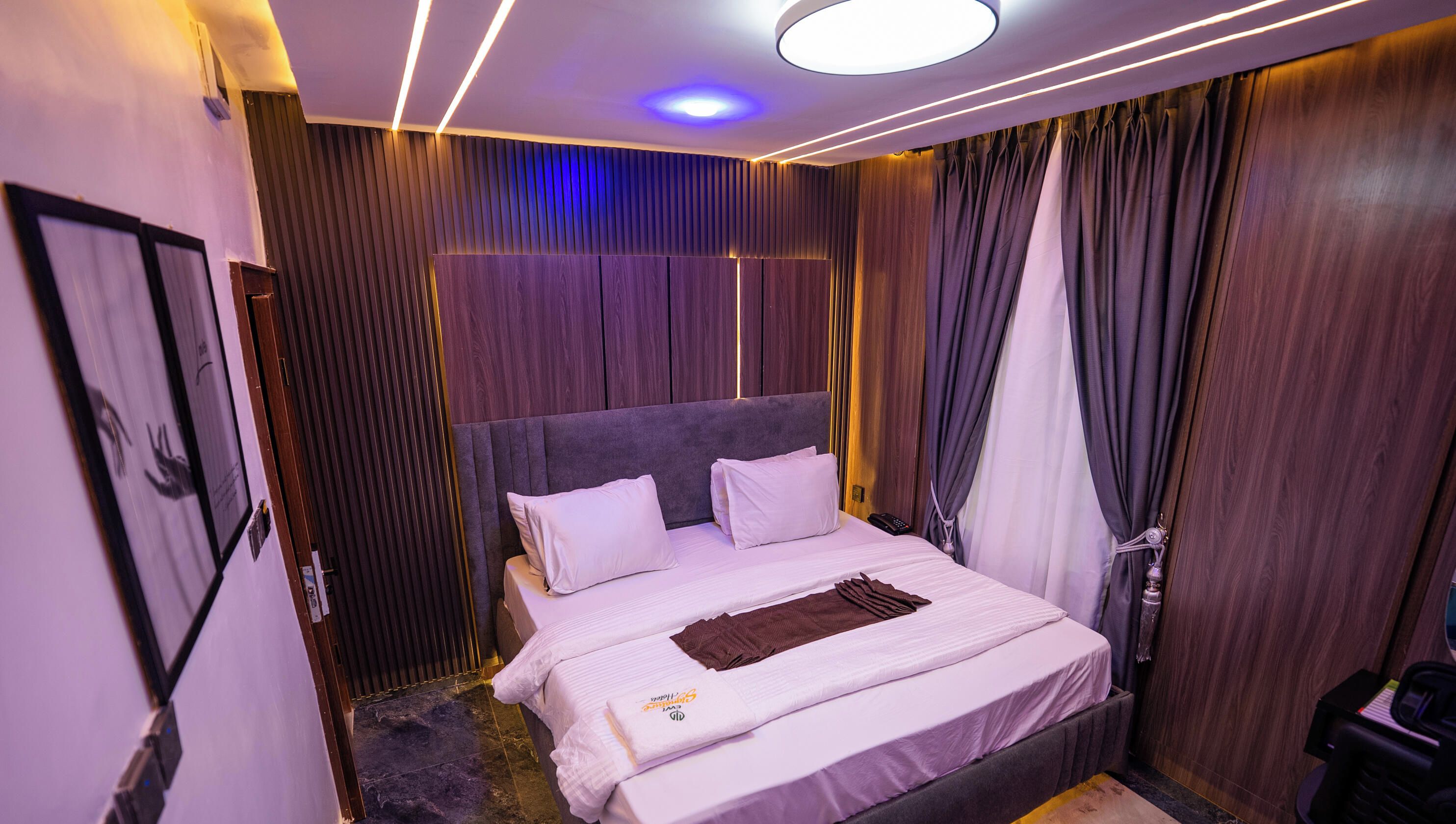 Una habitación de hotel con una cama grande, un cabecero y una lámpara en el techo.