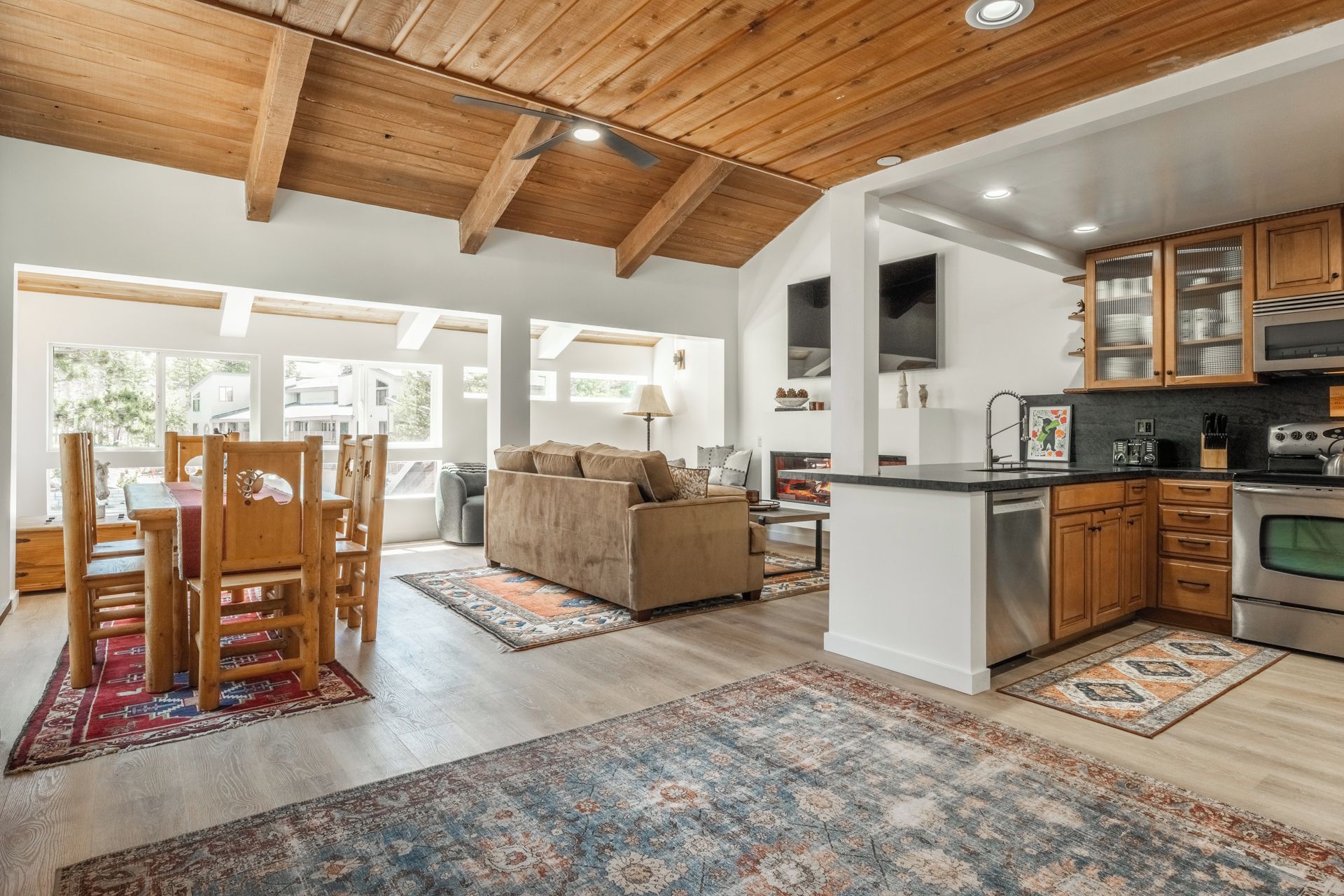A modern kitchen with wooden cabinets, a stainless steel oven, and a dining area with a wooden table and chairs.