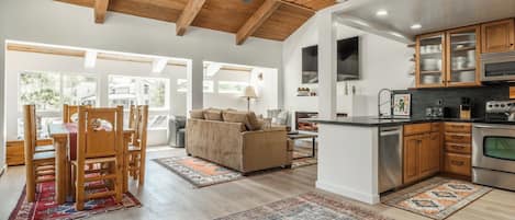 A modern kitchen with wooden cabinets, a stainless steel oven, and a dining area with a wooden table and chairs.
