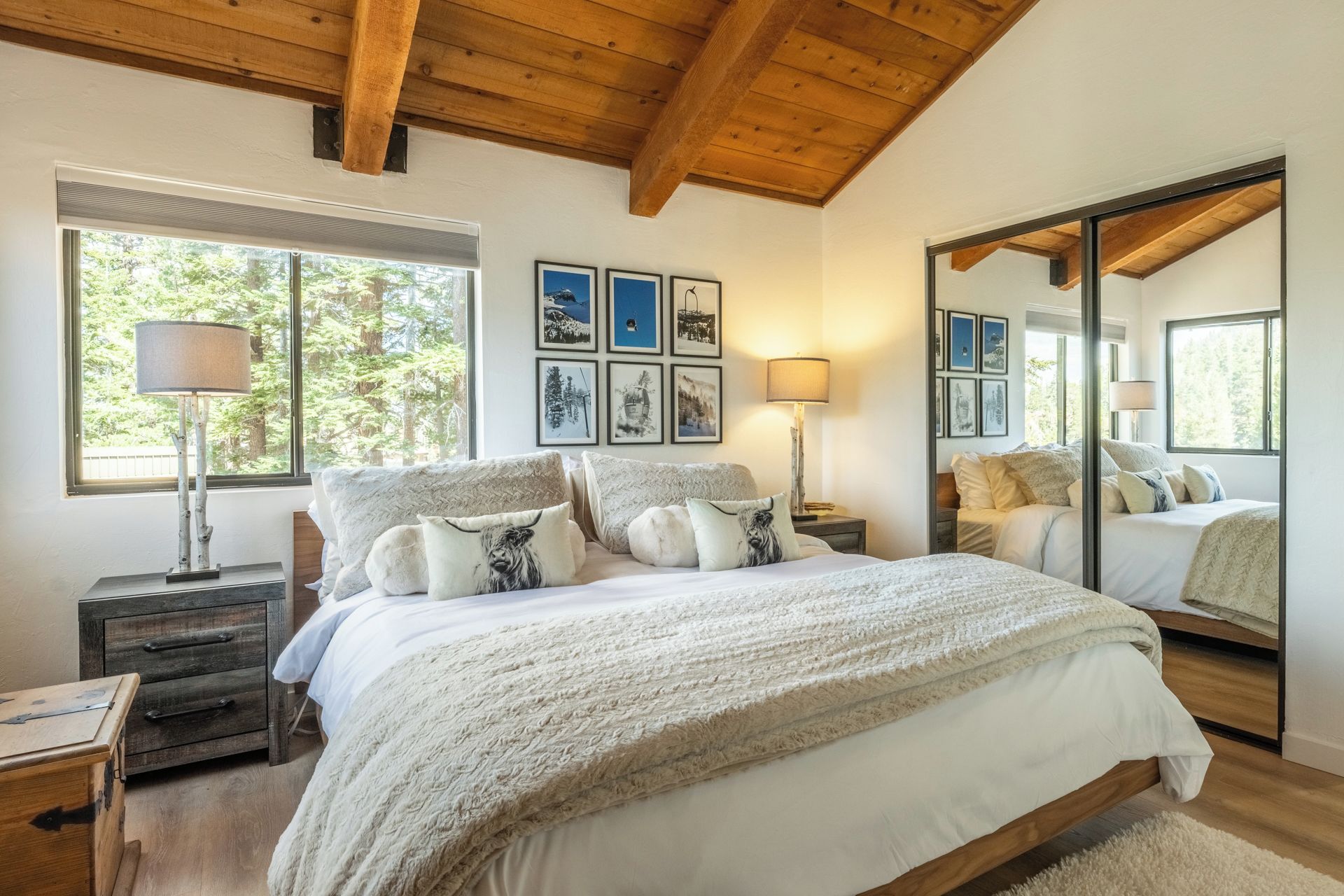 A bedroom with a large bed, a wooden ceiling, and framed pictures on the wall.