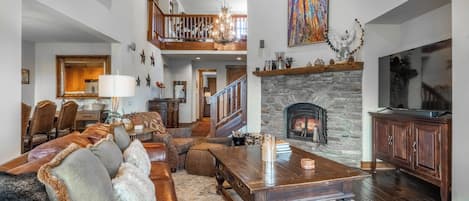 Una sala de estar amplia con chimenea, comedor y escalera que lleva a un nivel superior.