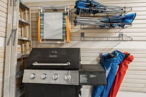 A kitchen with a grill, a wooden ladder, and a metal rack with cleaning supplies. - Lodges Condo Mountain Views 507 (Mammoth Lakes)