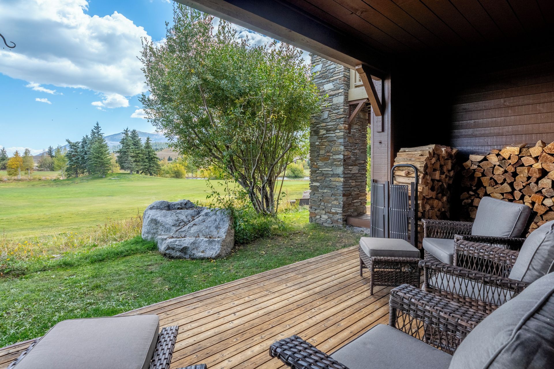 Eine Terrasse im Freien mit Korbmöbeln und einer Steinwand.