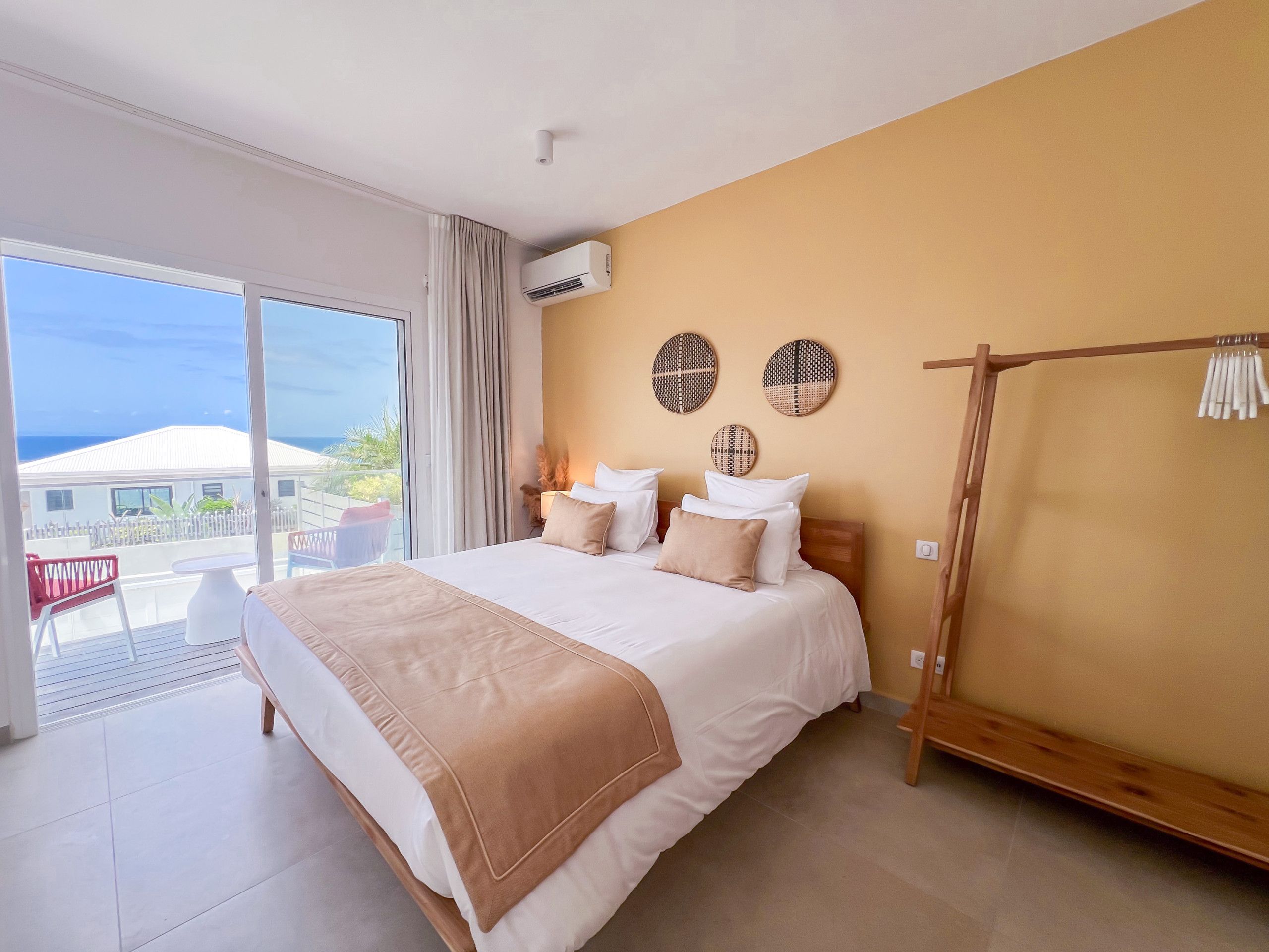 Une chambre d’hôtel avec un grand lit, un balcon avec vue et une armoire en bois.
