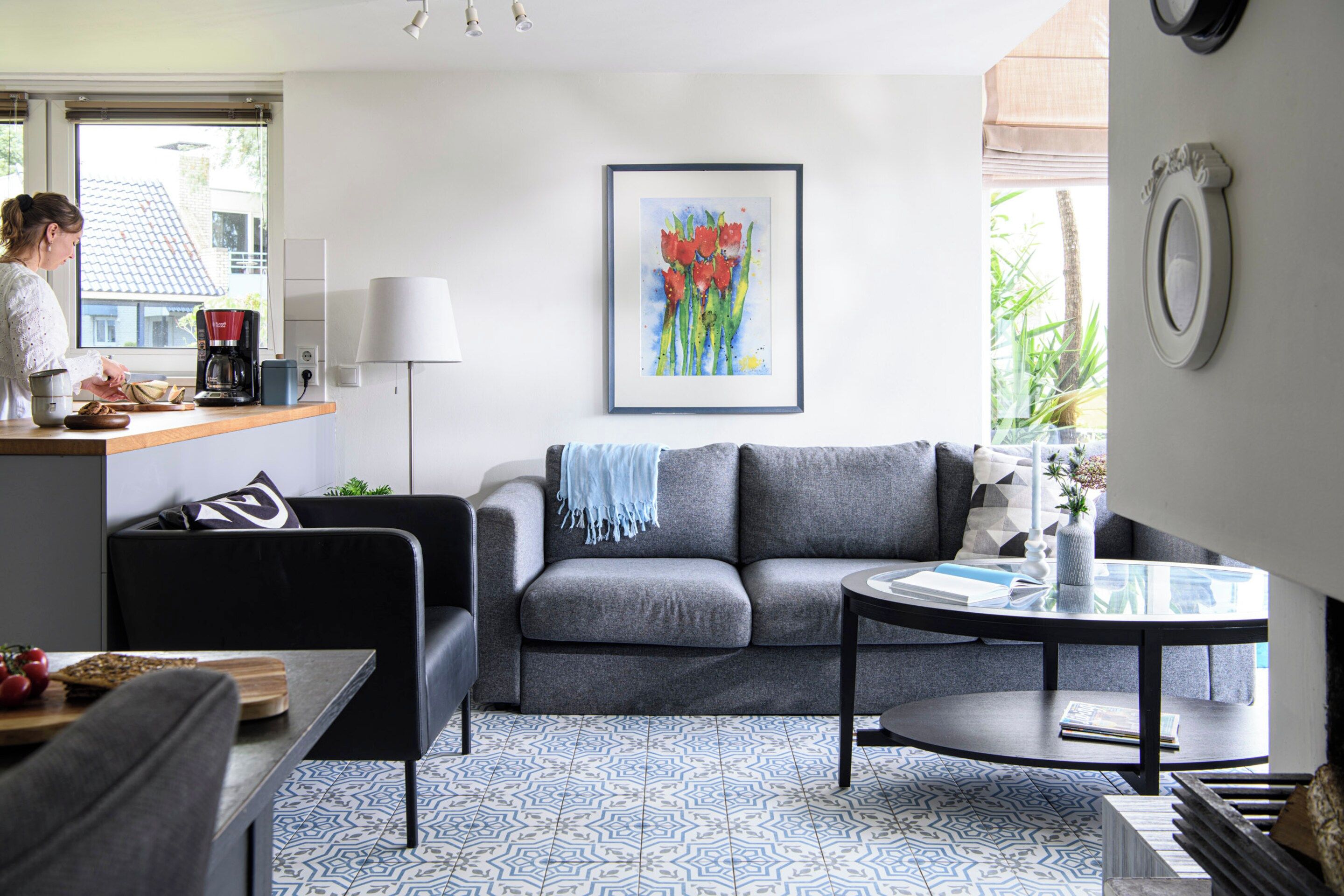 A modern living room with a grey sofa, a coffee table, and a patterned floor.