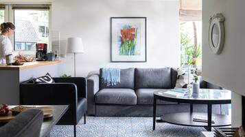 A modern living room with a grey sofa, a coffee table, and a patterned floor.