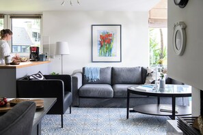 Una sala moderna con un sofá gris, una mesa de centro y un suelo con estampado.