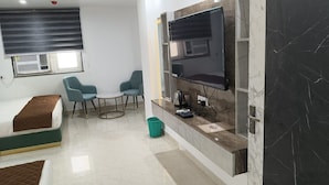 Habitación de hotel con cama, escritorio, dos sillas, televisor y minibar.