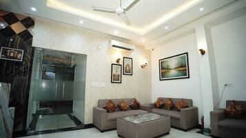 A modern living room with a sofa set, a coffee table, a ceiling fan, and artwork on the walls.
