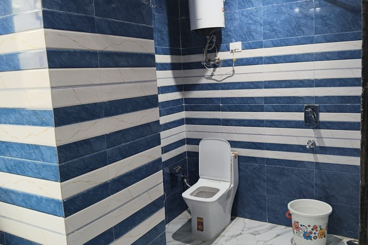 A bathroom with a toilet, a bidet, and a bucket.